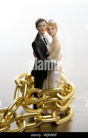 Metafora del matrimonio come una perdita di libertà. Figurine di nozze e catena d'oro Foto Stock