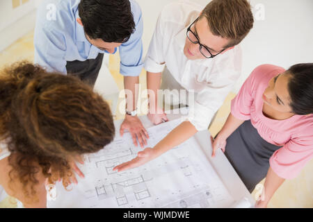 Elevato angolo di visione del business persone per discutere su blueprint alla scrivania in ufficio Foto Stock