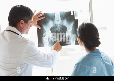 Vista posteriore del medico e infermiere esaminando xray in ospedale Foto Stock