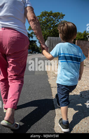 Una nonna si tengono per mano con suo nipote di un piccolo ragazzo di stagno delle anatre Foto Stock