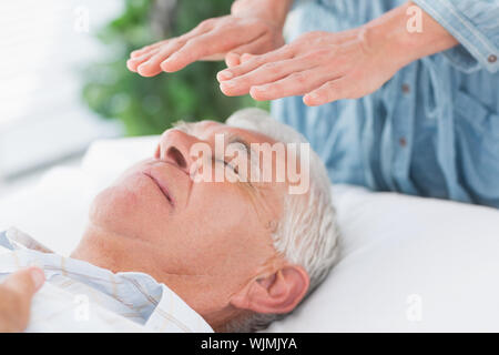 Terapista del massaggio reiki esegue su alti man a health spa Foto Stock