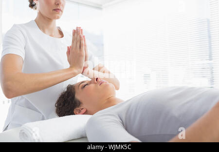 Terapista del sesso femminile dando trattamento Reiki per donna a health spa Foto Stock