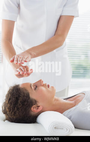 Terapista del sesso femminile di eseguire Reiki sulla donna a spa Foto Stock