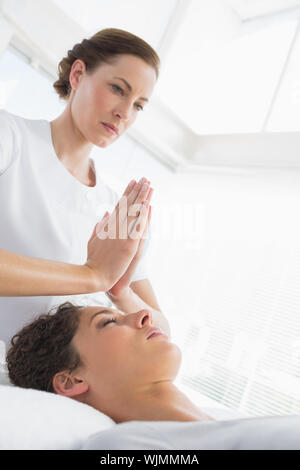 Terapista del sesso femminile dando trattamento Reiki per donna a spa Foto Stock