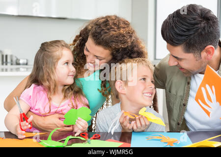 Sorridente giovane famiglia facendo arti e mestieri a tavola in casa in cucina Foto Stock