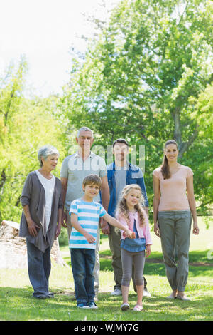 Lunghezza completa di una felice famiglia estesa a piedi nel parco Foto Stock