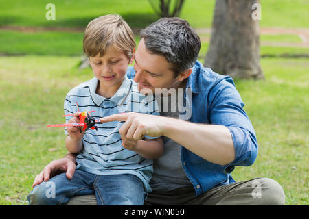 Ragazzo con aeroplano giocattolo seduto sul padre di giro al parco Foto Stock