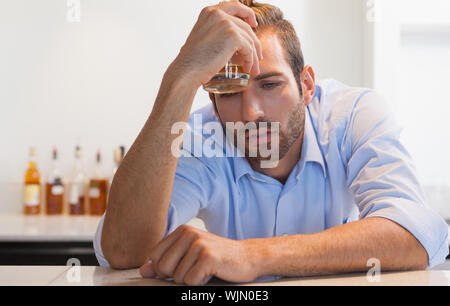 Imprenditore ubriaco innesto bicchiere di whiskey a testa presso il bar locale Foto Stock