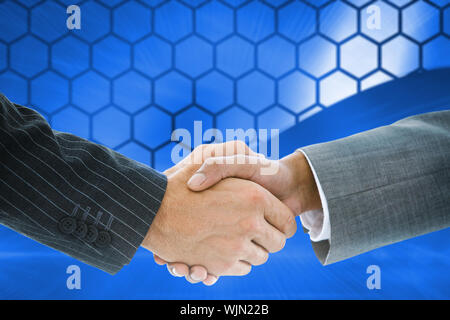 Immagine composita di handshake business contro gli esagoni su sfondo blu Foto Stock