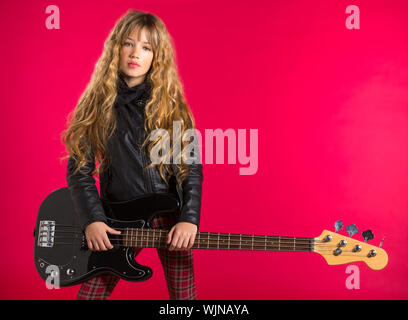 Blonde rock and roll girl bass guitar player su sfondo rosso Foto Stock