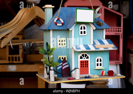Realizzati artigianalmente in miniatura casa ornamentali patterns sulla luce blu. Ha un piccolo giardino appeso il suo tetto. Foto Stock