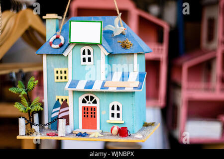 Realizzati artigianalmente in miniatura casa ornamentali patterns sulla luce blu. Ha un piccolo giardino appeso il suo tetto. Foto Stock