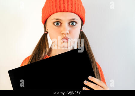Una bella ragazza in un Red Hat con grandi occhi spalancati trattiene un foglio nero Foto Stock