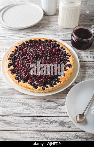 Torta di bacche con ciliegia, ribes, mora, mirtillo su servita bianco tavola di legno . Cheesecake. Foto Stock