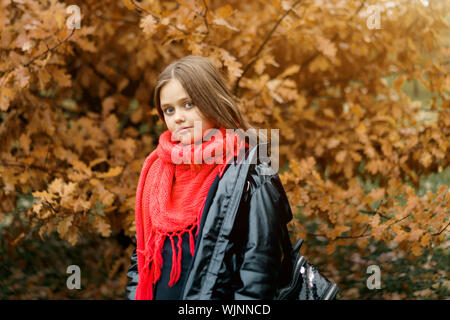 Bellissima con i capelli lunghi ragazza di età scolare avvolto in un arancio luminoso sciarpa Foto Stock