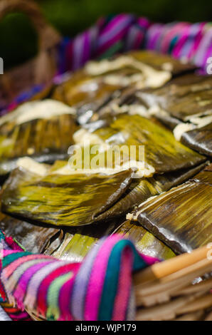 Tradizionali di pollo messicano tamales coperto con lastre di banana servita su un vassoio Foto Stock