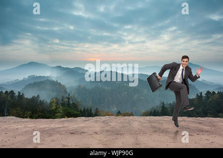 Happy businessman in un hury contro la paesaggistica campagna con le montagne Foto Stock