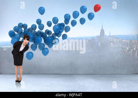 Imprenditrice ha sorpreso la piegatura contro molti palloncini colorati in camera con città sulla parete Foto Stock