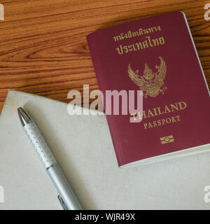 Passaporto thai con i notebook su legno sfondo tabella Foto Stock