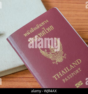 Passaporto thai con i notebook su legno sfondo tabella Foto Stock