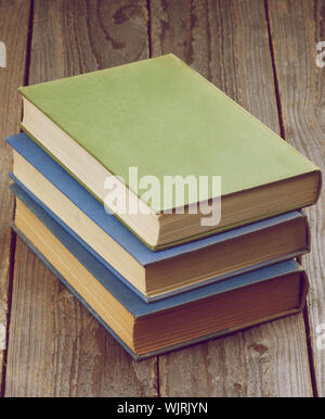 Pila di tre libri vecchi isolate su legno rustico sfondo. In stile retrò Foto Stock