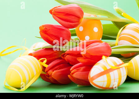 Colorato di rosso la Pasqua ancora in vita con delicata molla freschi tulipani e dipinte a mano tradizionale Uova di Pasqua disposti su uno sfondo bianco con copyspac Foto Stock