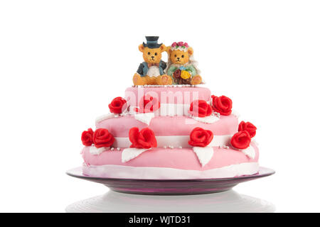 Rosa torta di nozze con rose rosse e portano la sposa e lo sposo sulla sommità isolate su sfondo bianco Foto Stock