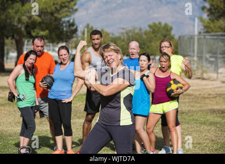 Carino donna di mezza età flettendo i muscoli con lezione di fitness Foto Stock