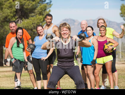 Grinning donna matura bollitore di sollevamento pesi a campana con il gruppo Foto Stock