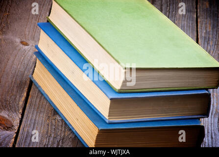 Pila di tre libri vecchi isolati su rustico sfondo di legno Foto Stock