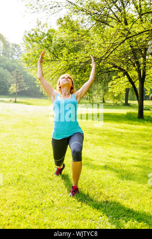 Femmina istruttore yoga in guerriero spirituale pongono al green park Foto Stock