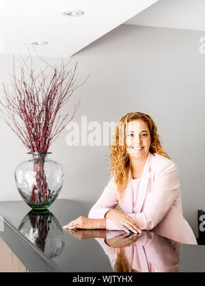 Receptionist in piedi presso il banco di ricevimento in ufficio Foto Stock