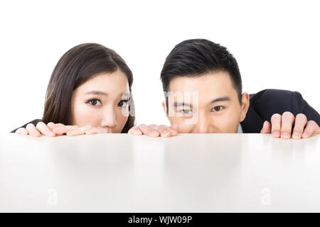 Asian business l uomo e la donna nascondere sotto il tavolo e guardando da qualche parte. Foto Stock