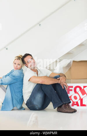 Vista laterale verticale di una coppia sorridente con le caselle in una nuova casa Foto Stock