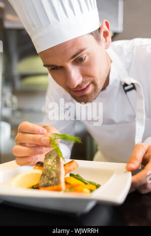Primo piano di un concentrato maschio guarnitura dello chef in cucina il cibo Foto Stock