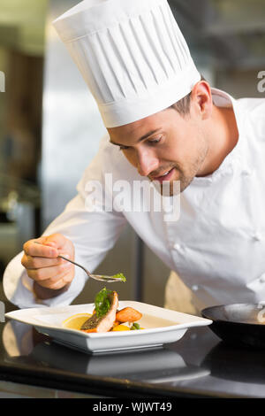 Primo piano di un sorridente maschio guarnitura dello chef in cucina il cibo Foto Stock