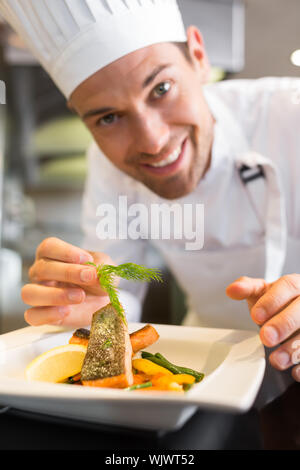 Primo piano di un sorridente maschio guarnitura dello chef in cucina il cibo Foto Stock