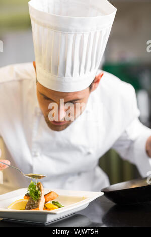 Primo piano di un concentrato maschio guarnitura dello chef in cucina il cibo Foto Stock