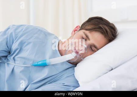 Paziente di sesso maschile di indossare le maschere di ossigeno giacente sul letto di ospedale Foto Stock