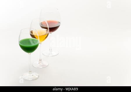 Tre bicchieri alti su sfondo bianco riempito con: bianco, vino rosso e verde cocktail Foto Stock