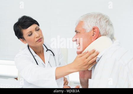 Close-up di un medico donna esaminando un senior pazienti collo all ufficio medico Foto Stock