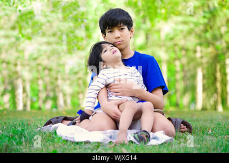 Young Teen boy caring per disabili fratello, guardando in alto nel cielo Foto Stock