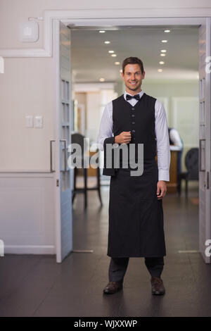 Bello il cameriere sorridente in telecamera in un lussuoso ristorante Foto Stock