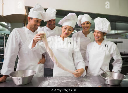 Guardare gli chef pasticcere tratto pezzo di pasta in una cucina commerciale Foto Stock