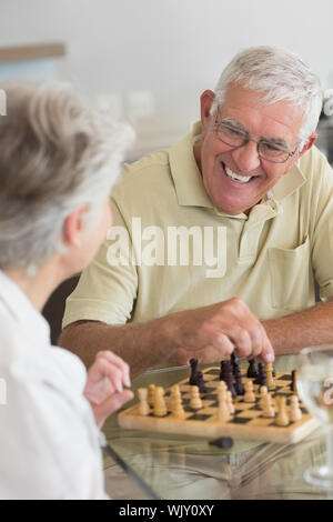 Coppia senior giocando a scacchi e avente il vino bianco a casa in cucina Foto Stock
