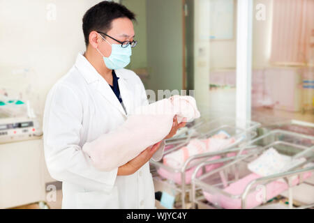 Medico tenendo un neonato in una sala per neonati Foto Stock