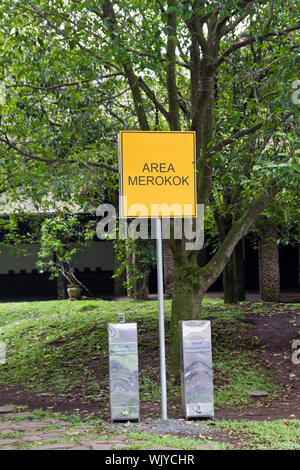 Area fumatori e digital signage in indonesiano mescolare con la lingua inglese Foto Stock