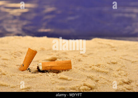 Alcuni mozziconi di sigaretta su di una spiaggia di sabbia Foto Stock