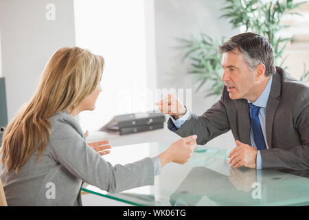 Due arrabbiato co lavoratori sostenendo in un ufficio Foto Stock