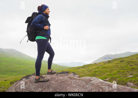 Donna in piedi sulla roccia ammirando la vista Foto Stock